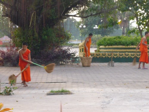 Monks brushing up leaves at Pha That Luang, Vientiane, laos